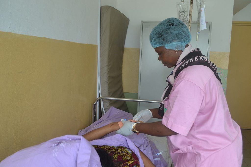 Nurse caring for patient in hospital bed